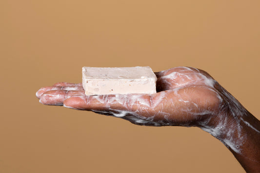 person washing hands with soap isolated on orange background